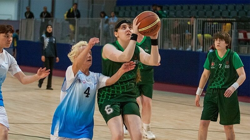 Ungdomsspelare tävlar om bollen i en basketmatch inomhus