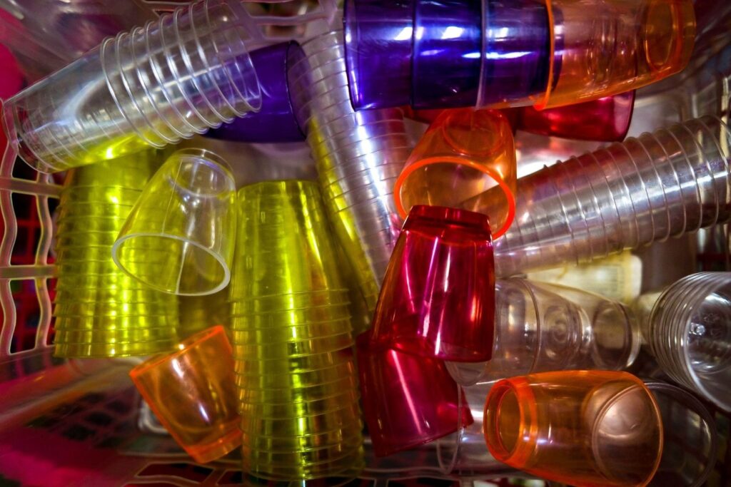 Färgglada återanvändbara plastmuggar och rör staplade tätt tillsammans