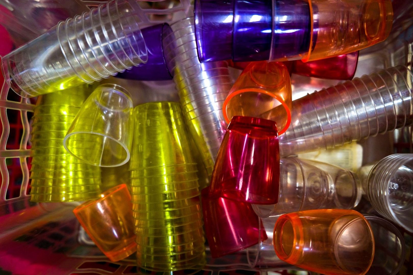Färgglada återanvändbara plastmuggar och rör staplade tätt tillsammans