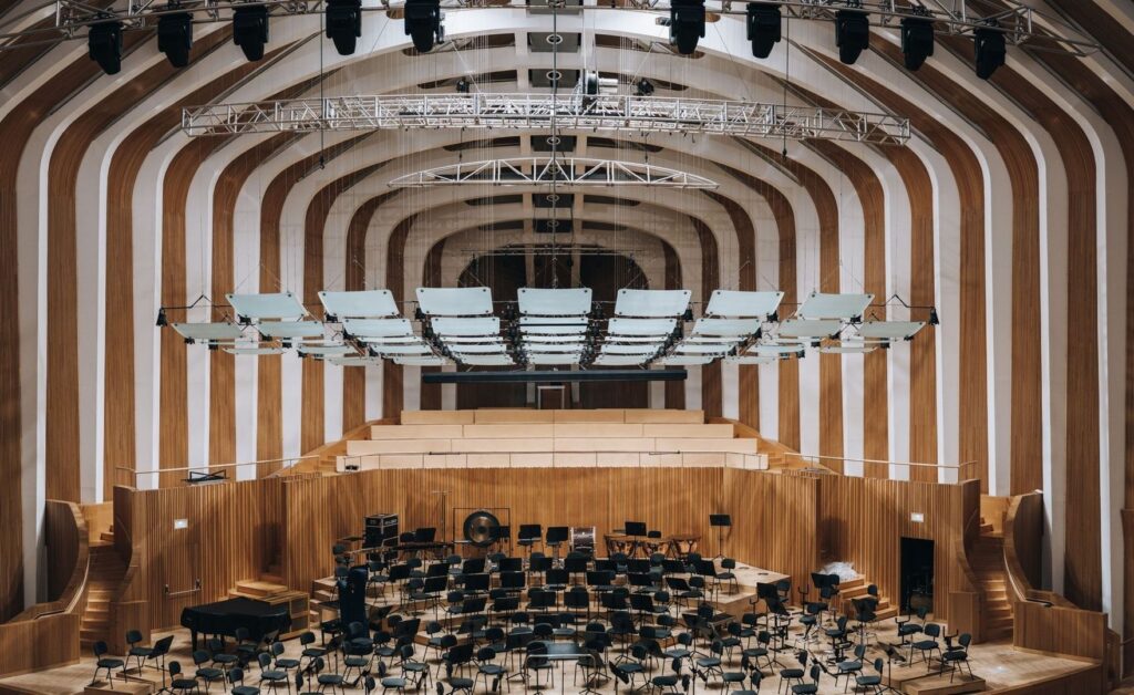 Konsertsal med orkesterscen och nedhängda akustikpaneler i taket