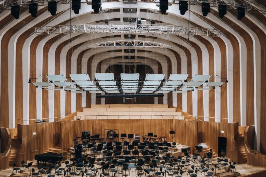 Konsertsal med orkesterscen och nedhängda akustikpaneler i taket